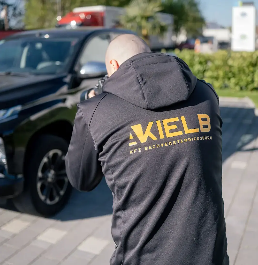 Kfz-Gutachter mit Logo „KIELB“ auf dem Rücken beim Fotografieren