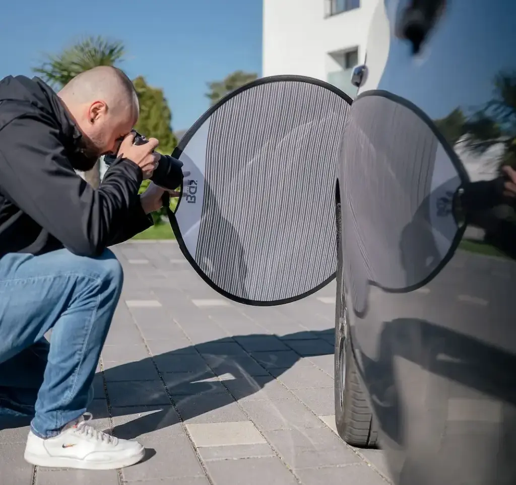Kfz-Gutachter fotografiert reflektierende Lackfläche am Fahrzeugheck mit Polarisationsschirm