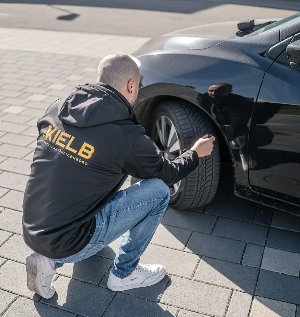 Kfz-Gutachter untersucht einen Schaden im Bereich des Radkastens – KIELB Sachverständiger mit Firmenjacke bei der Prüfung